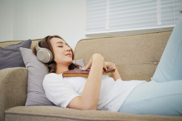 A woman is laying on a couch with a book in her hand
