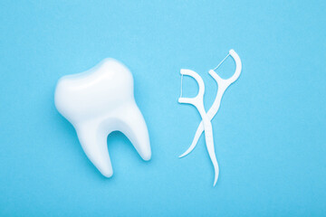White healthy tooth with dental floss on blue. Oral dental care products, hygiene cleaning personal use lifestyle concept