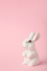 White ceramic rabbit on pink background. Vertical photo