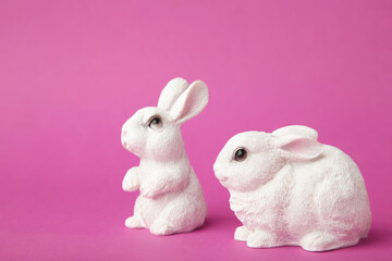 White ceramic rabbit on pink background. Space for text