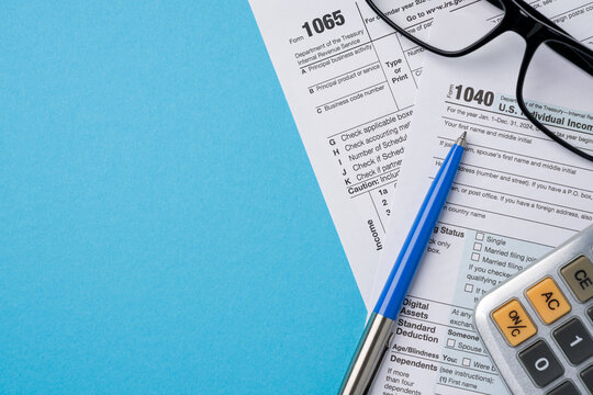 Top view of tax forms, calculator and pen on blue table