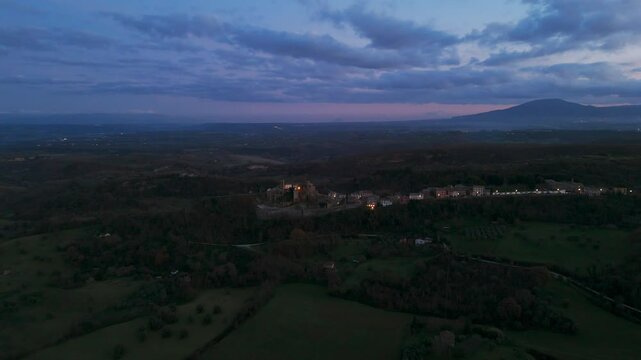 Celleno village illuminated, surrounding landscape at sunset, Viterbo in Italy. Aerial drone