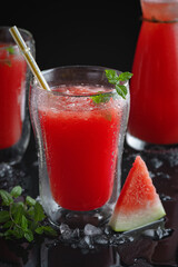Summer cold drink with watermelon and mint on a black wooden background.