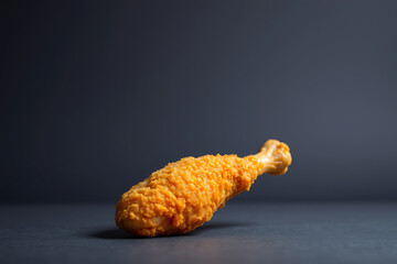 Obraz premium Large, crispy fried chicken leg stock-image with golden-brown breading, showcasing the perfect crunch and juicy interior, served on a plain background to highlight its delicious, irresistible texture.