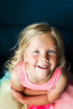 Blonde girl wearing rainbow outfit smiling warmly at the camera.