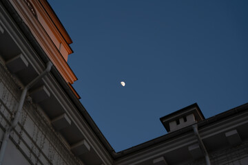 The waxing Moon. The moon is on the corner of the building. Minimalism, evening