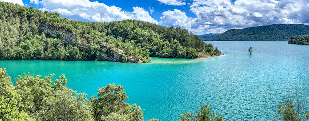 Obraz premium view of Mediano lake in Spain bordered by wooded hills with turquoise water