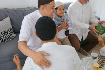 Obraz premium Young Little Boy Kneeling And Handshaking His Father On Eid Al Fitr