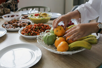 Woman Sorting a Bowl of Fruits With Various Side Dishes on The Table for Celebrating Eid Al Fitr