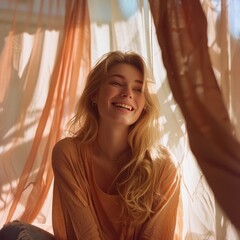 Young blonde woman with long wavy hair laughing in nature, wearing a cozy brown sweater. Her joyful expression and the autumn foliage create a warm and relaxed outdoor atmosphere.