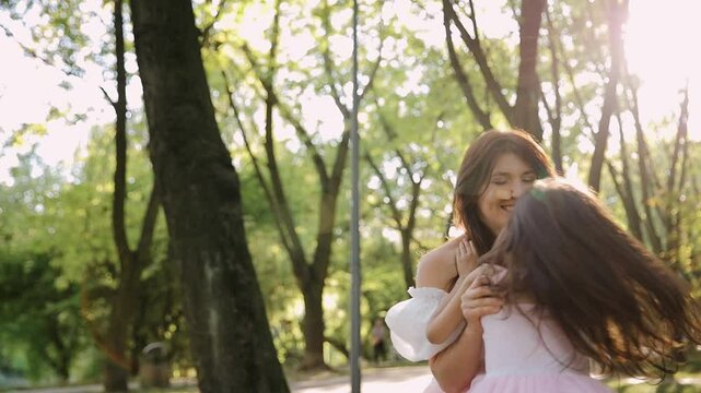 A mother and daughter share a happy moment together outdoors in a sunny park, illustrating themes of love, connection, and joy in a nature-filled setting.