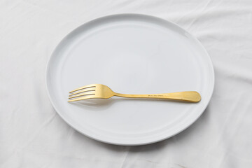 A plain ceramic plate resting on a fabric table cloth, symbolizing simplicity and restriction, representing diet and mindful eating.