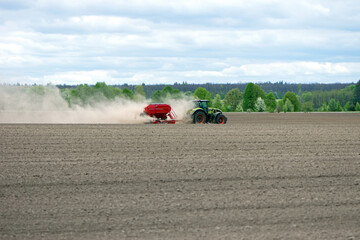 Obraz premium tractor in a field, planting crops on an agricultural field. tractor working in the field, harvesting, business, agriculture. soil preparation, spring season. Seasonal work. Farmland. Diesel. Ukraine