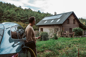 Man charging electric car, checking progress in app.