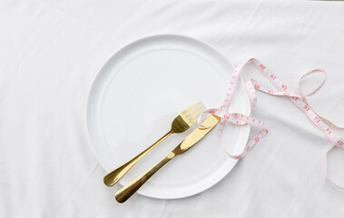 An empty ceramic plate wrapped with a waist measurement tape, symbolizing diet, nutrition, and healthy lifestyle planning.