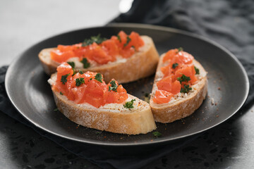 Bruschettas with salmon and cream cheese on black plate closeup