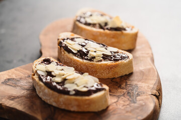 Rustic ciabatta with organic chocolate cream and almond flakes on olive wood board