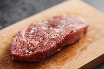 Raw ribeye steak spiced and ready to cook on oak board