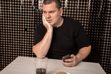 Sad man with phone, thoughtful male browsing technology, feelings of disappointment and sorrow.