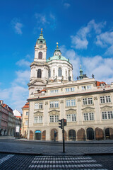 Obraz premium Low angle view of St. Nicholas Church in Prague, Czech Republic, highlighting its baroque architecture against a vibrant blue sky