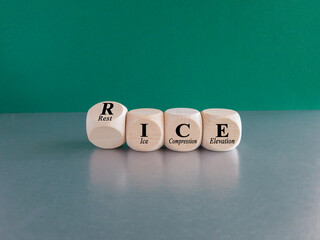 The acronym RICE (rest, ice, compression, elevation) on wooden cubes. Beautiful grey table green background. Symbol for the treatment for sprains and strains.