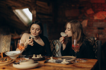 Two Women Enjoying Dumplings and Drinks in a Cozy Restaurant Setting