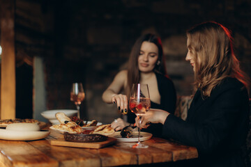 Two Women Sharing Dinner and Drinks in a Cozy Rustic Restaurant Setting