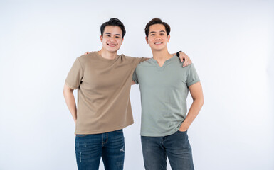 Fototapeta premium Two smiling men pose together, arm in arm, against a clean, white background. Casual attire and genuine smiles convey camaraderie.