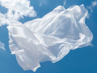 A white sheet of fabric is flying in the air on a clear blue day