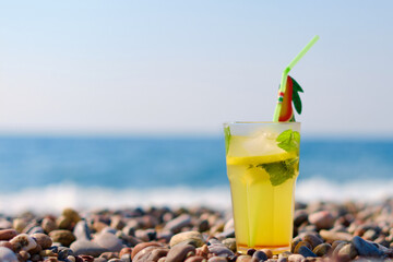 Vibrant drink decorated with fruit slice sitting on sunlit beach captures essence of tropical leisure and outdoor relaxation by the sea