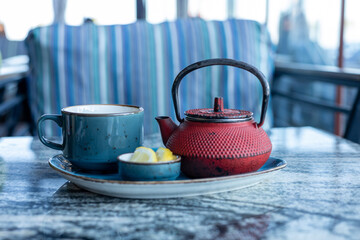 Relaxing tea time with a red teapot and blue cup on a marble table