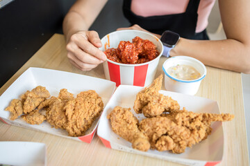 Woman is eating delicious fried chicken in a restaurant