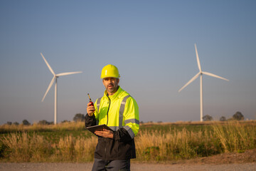 Engineer man working with tablet at windmill farm Generating electricity clean energy. Wind turbine farm generator by alternative green energy.
