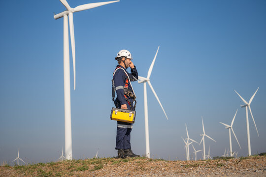 Engineer man working at windmill farm Generating electricity clean energy. Wind turbine farm generator by alternative green energy.