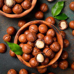 Wooden bowl filled with macadamia nuts. Roasted delicious nuts. Top view.