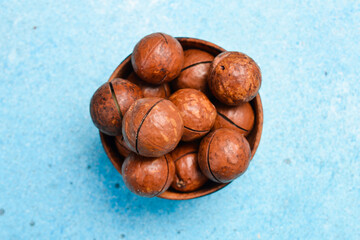 Obraz premium Roasted delicious macadamia nuts on a blue stone background. Top view.