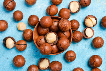 Roasted delicious macadamia nuts on a blue stone background. Top view.