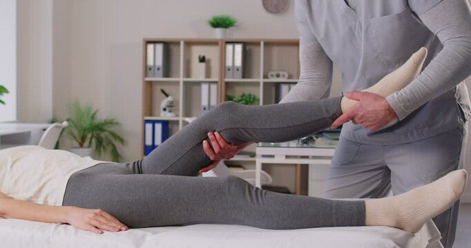 Manual therapy exercise, leg rehabilitation in clinic, physical therapist doing manipulative therapy medical room, female patient lying on med coach to massage after sport trauma, reduce disability 