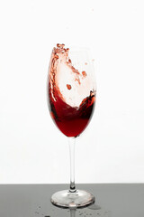 Red wine in glass. Splashes of red wine. Transparent glass with wine or juice on white background. Isolated object.