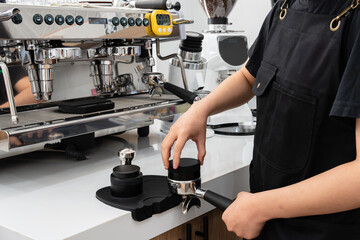 Barista making coffee machine brewing espresso in to glass cup.Barista while preparing and working with coffee machine and making espresso coffee from arabica coffee beans.