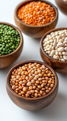 Fototapeta premium Wooden bowls filled with various grains, legumes, and beans on white surface