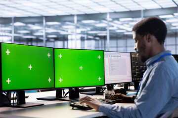 Engineer in server hub ensuring data remains shielded from potential threats using chroma key PC....