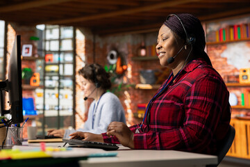 Cheerful call center operator talking in headset microphone, helping customers regain access to...
