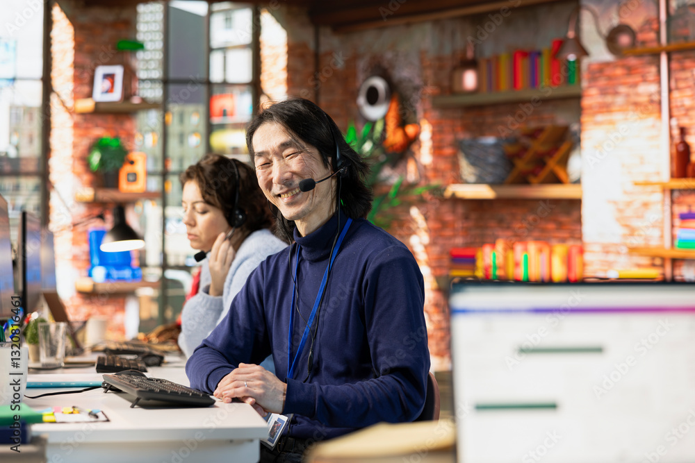Poster portrait of cheerful asian call center agent talking with customer, adhering to company communicatio