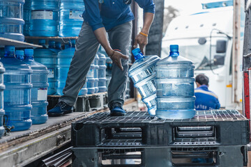 worker transfer drinking water bottle from production plant line to truck for customer market
