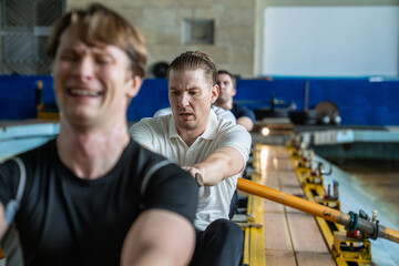 Dedicated tired exhausted male rowing team trains endurance, practicing paddle rowing before contests. Exhausted sportsmen in professional academic sport or hobby with cardio and strength exercises
