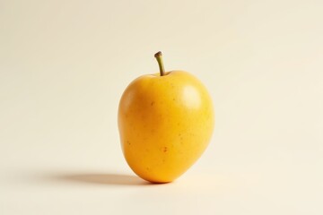 Yellow hybrid fruit resembling an apple and a mango, isolated on a neutral background.