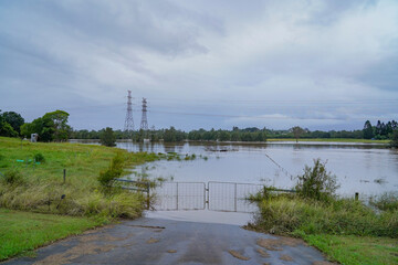 Flooded Rural Landscape with Submerged Gate and Power Lines Under Cloudy Sky