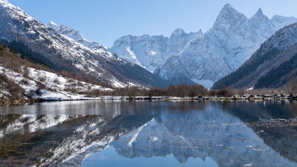 Fototapeta premium Dombay, Karachay-Cherkessia. Teberda National Park. Lake Tumanly-Gel or Tumanly-Kol (Misty Lake) is in valley of Gonachkhir River. Snowy peaks of Mount Chotcha are reflected in lake as in mirror.