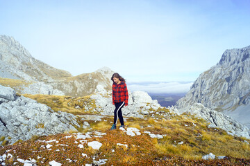 Obraz premium Shot List travel: woman walking in beautiful mountainous area on sunny autumn day (Komovi Nature Park, Montenegro). Solo nature travel: female hiker high in the mountains. Exploring the Balkans.